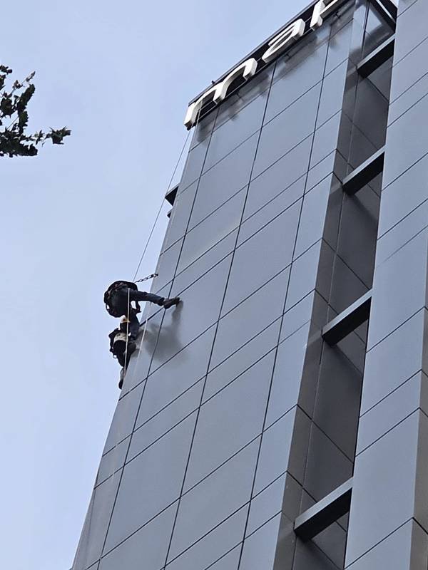 rope access technicians repairing façade cladding on a high-rise in Singapore